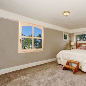 Simple bedroom with carpet, and white bedding.
